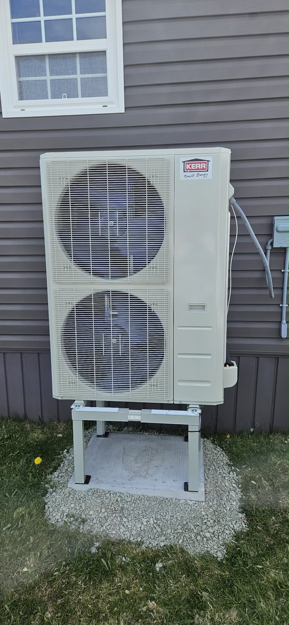 Kerr large outdoor unit on grey siding home — gravel bed
